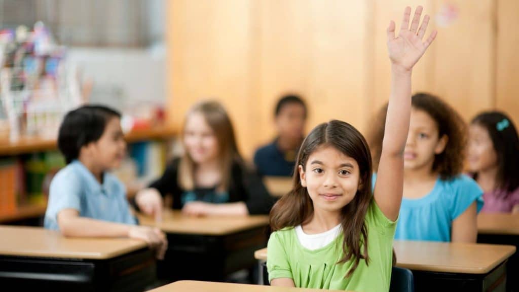 girl raising her hand in class